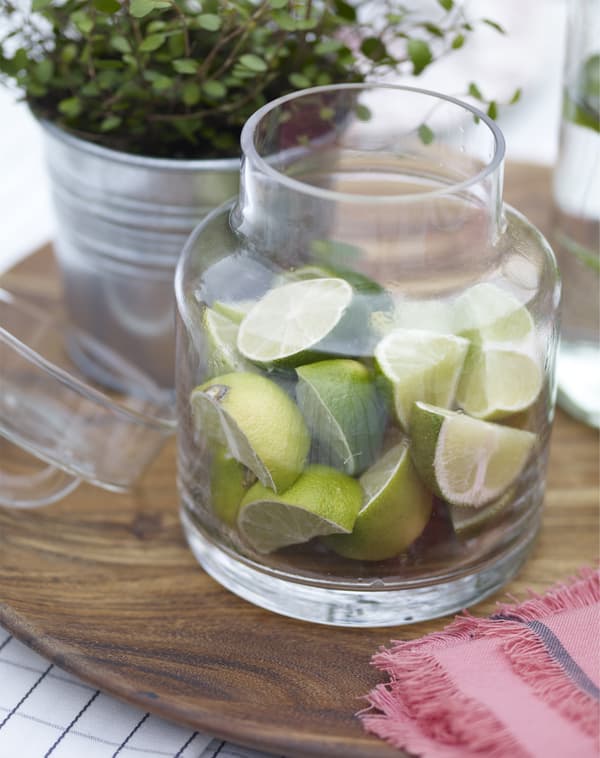 Lime wedges in a glass jar and a wooden tray.