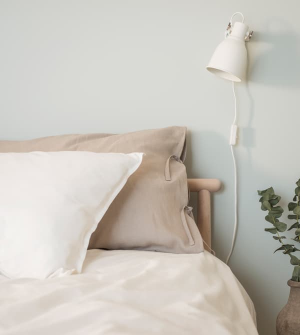 Linge de lit en lin naturel dans une chambre au mur peint vert clair