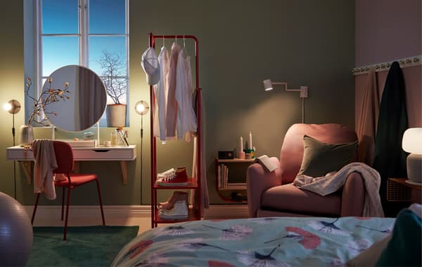 Link to IDEA blog 'Bedtime routines to wake up refreshed' - image of a dim bedroom with a make-up nook, clothes rack and reading corner with recliner.