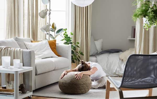 Link to IDEAS blog 'Create space for well-being habits at home' - image of a woman stretching in a living room.