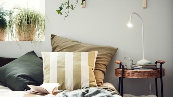 Link to 'Ideas to renew your home with cushions' - image of several cushions in different covers on a bed near a window.