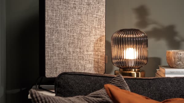 Link to 'Setting up a smart home' - image of a black FÖRNUFTIG air purifier with a lamp and some books.