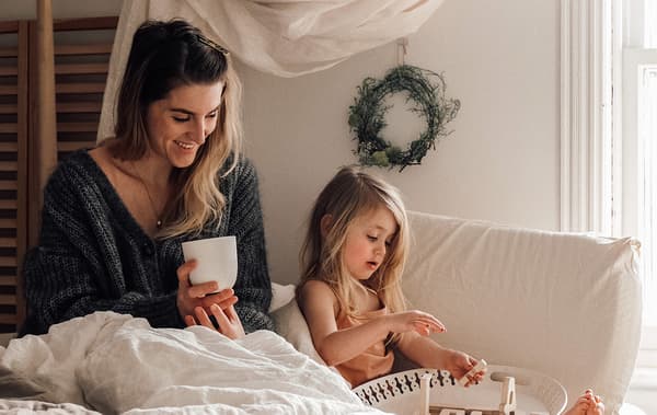 Link to 'Step into a Japandi-inspired bedroom for mother and daughter' IDEAS blog - image of Emilie and her daughter Brook on a bed with white linens.