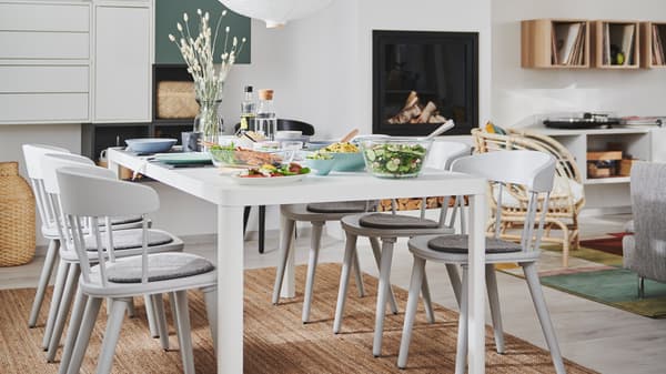 L’intérieur d’un séjour et salle à manger deux en un avec cheminée, rangements muraux et une table de salle à manger TINGBY entourée de chaises OMTÄNKSAM.