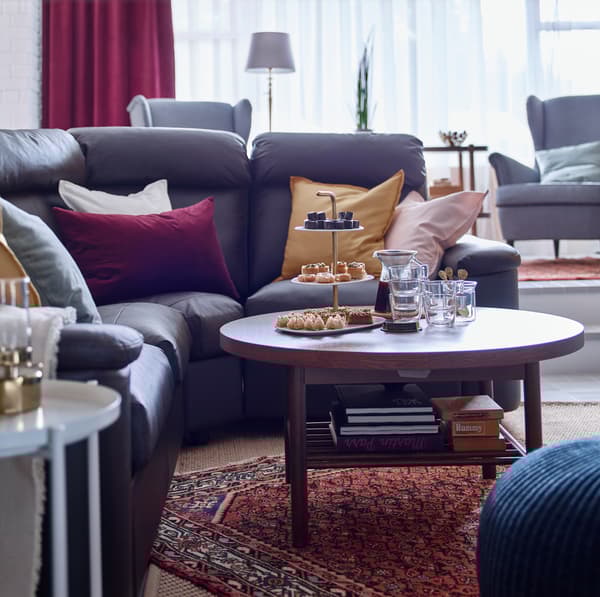 LISTERBY round brown wood coffee table with shelf underneath storing books and boardgames.