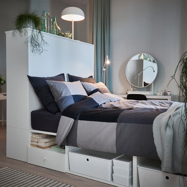 Lit blanc avec taies d'oreiller et housse de couette en noir et gris, dans une chambre grise et verte.