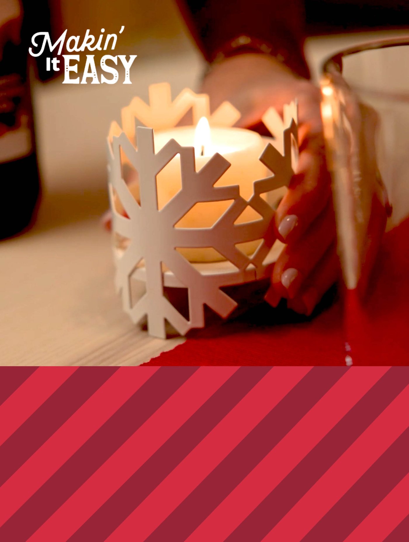 Lit candle in a white snowflake holder on a table with red accents; text reads “Makin’ It EASY.”