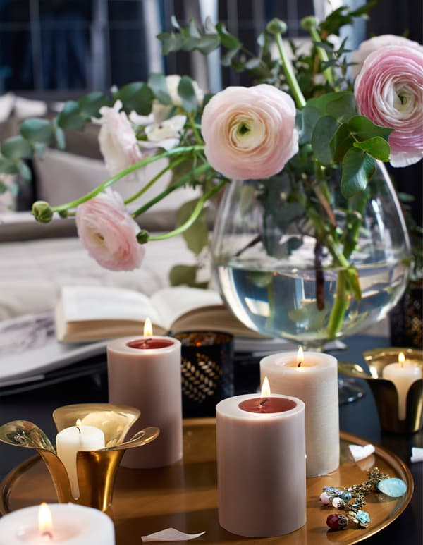 Lit candles and fresh flowers on a bedroom table.