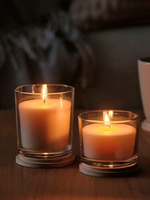 Lit candles on a coffee table beside flowers, creating a warm and cozy living room scene.