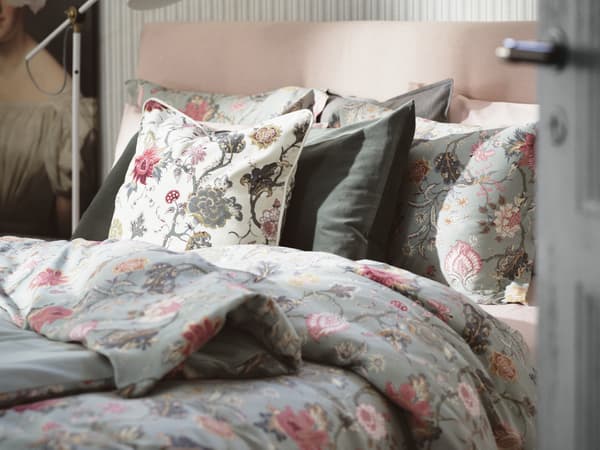 Lit habillé d’une housse de couette à motifs floraux en rose et vert clair et de taies d’oreiller assorties.