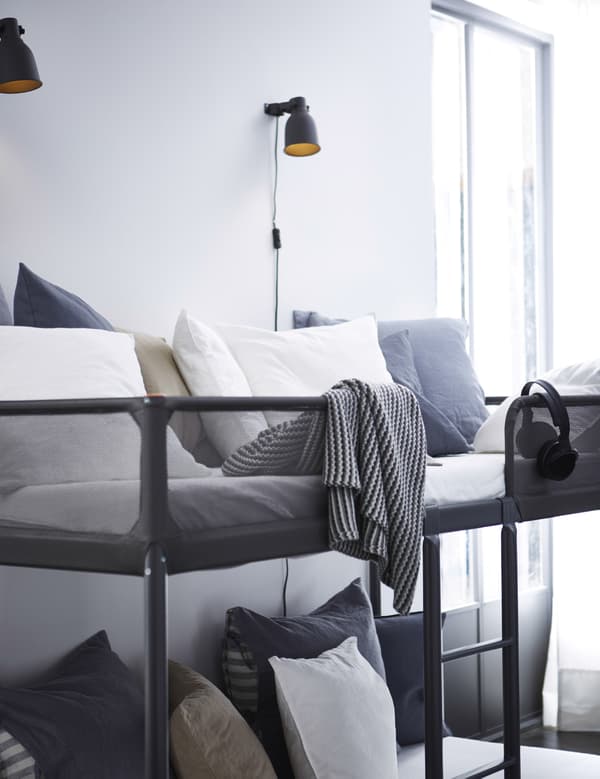 Lits superposés dans un séjour avec oreillers gris et blancs.