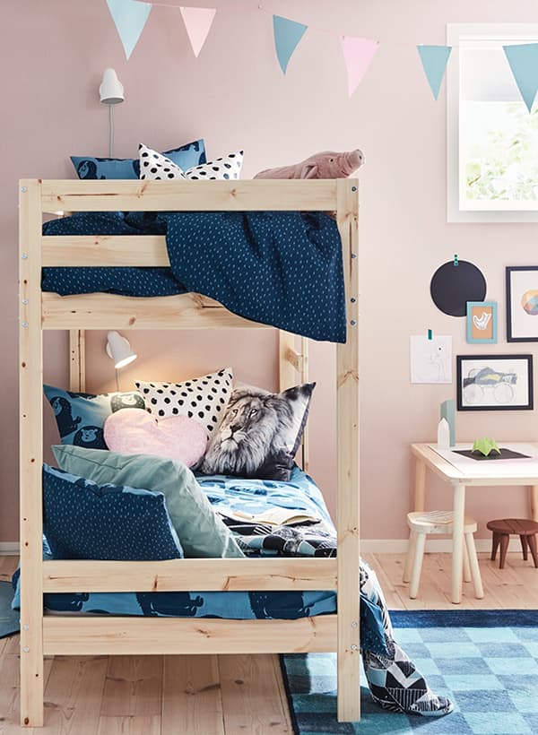Lits superposés MYDAL dans une chambre d'enfants aux murs rose pâle, le lit du bas servant de divan