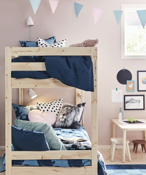 Lits superposés MYDAL en bois, coussins moelleux et jetés invitants dans une chambre d’enfant