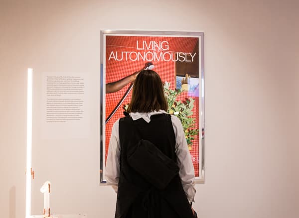 คนๆ หนึ่งมองไปที่โปสเตอร์ที่มีชื่อว่า 'Living autonomously'