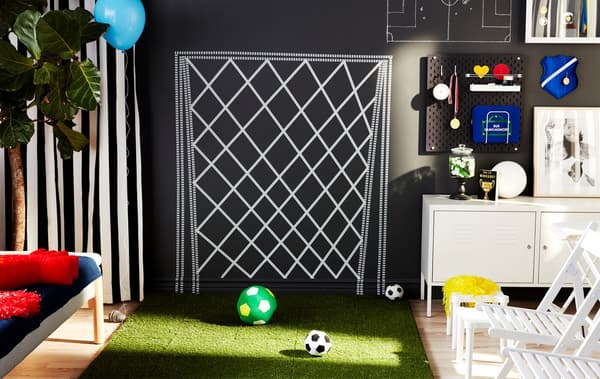 Living room decorated to replicate a football field with an artificial pitch and goal painted on the wall
