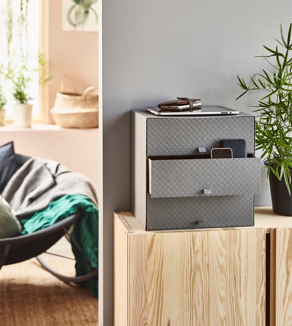 Living room storage can be as simple as a mini chest like PALLRA in dark gray from IKEA. It has three drawers and can hold papers, phones and other clutter to keep your living room calm and clean.