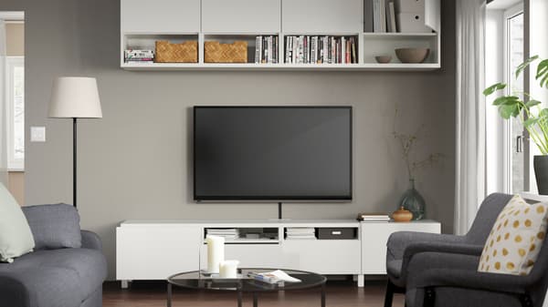 Living room that includes besta TV storage and above TV storage with a dark colored coffee table, sofa and two arm chairs
