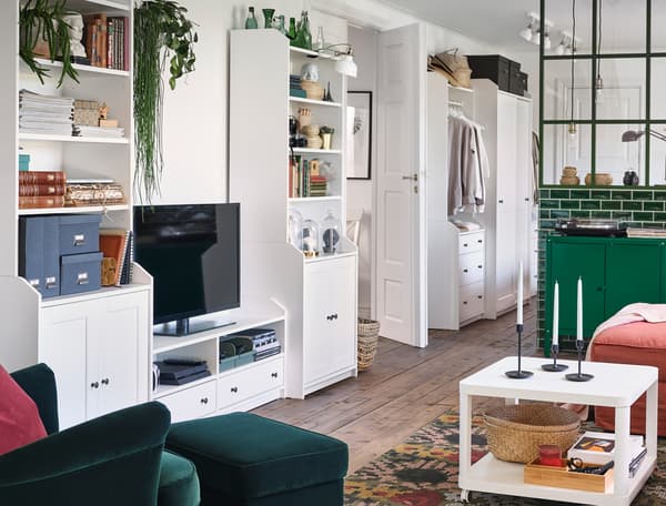 Living room where one wall is covered by a combination of white HAUGA furniture with functional and decorative storage.