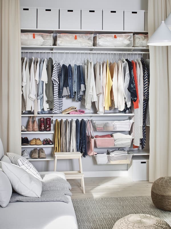 Living-room where one wall is fitted with open, floor-length curtains, revealing a wall-wide wardrobe arrangement.
