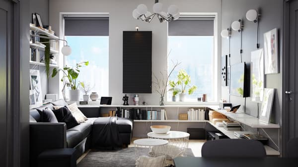 Living room with a black sofa-bed with chaise lounge, white shelves, a wall-mounted cabinet and a dark gray rug.