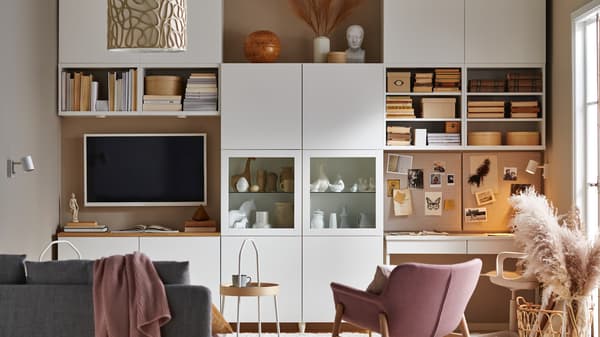 Living room with built-in wall storage units combining books decor a TV and a workspace with a bulletin board