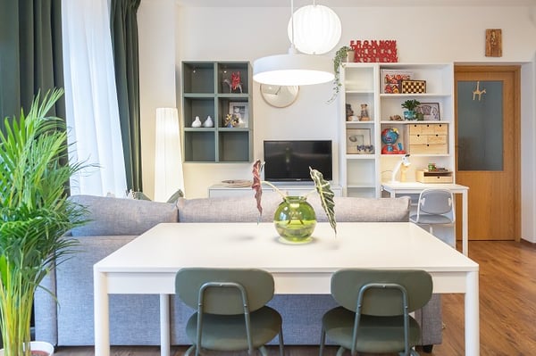 Living room with dining table, grey sofa, and TV wall unit.