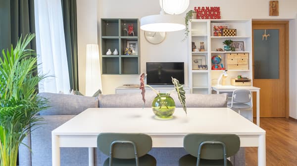 Living room with dining table, grey sofa, and TV wall unit.