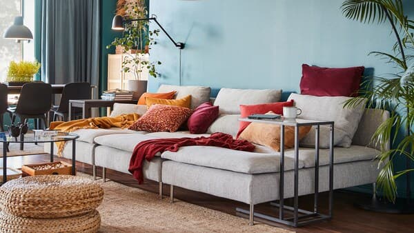 Living room with light gey SÖDERHAMN sofa with orange/red cushions.