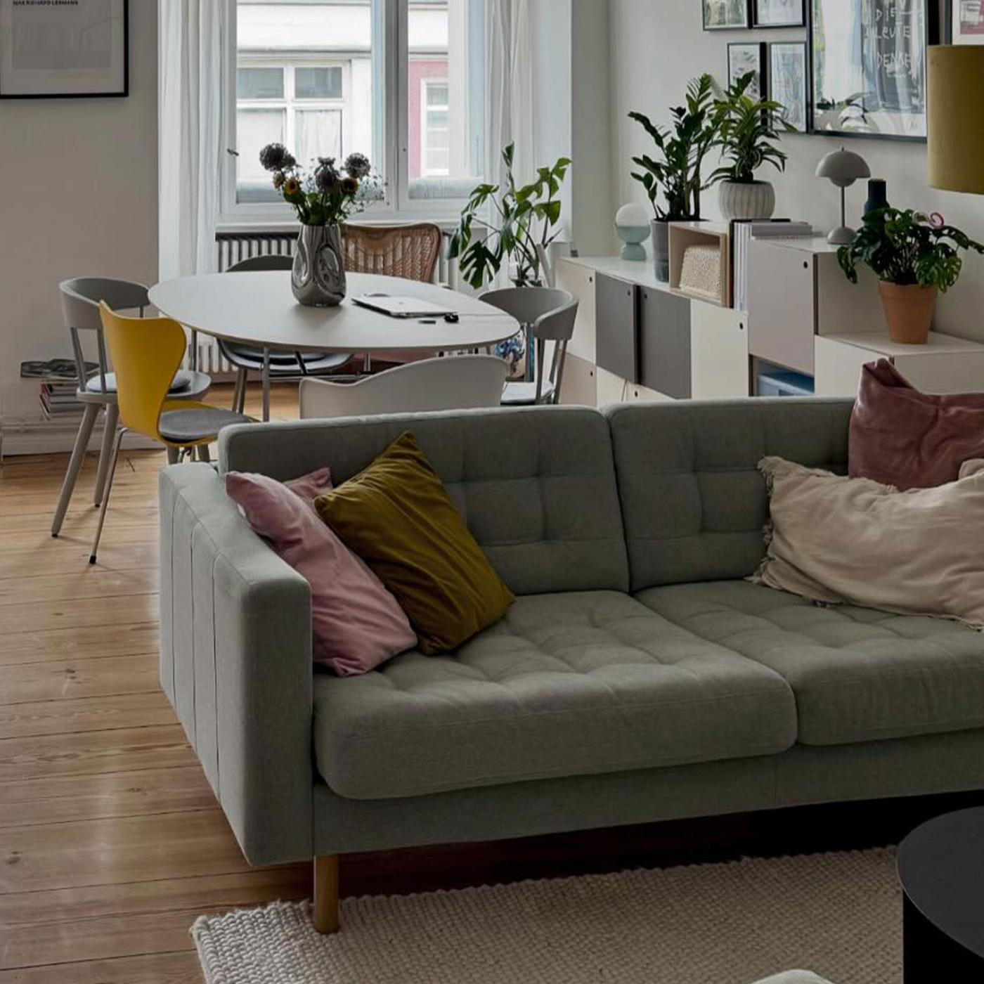 Ljusgrå LANDSKRONA tygsoffa stårnde i rum med öppen planlölsning. 