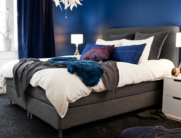 Llit continental gris en un dormitori elegant amb parets de color blau