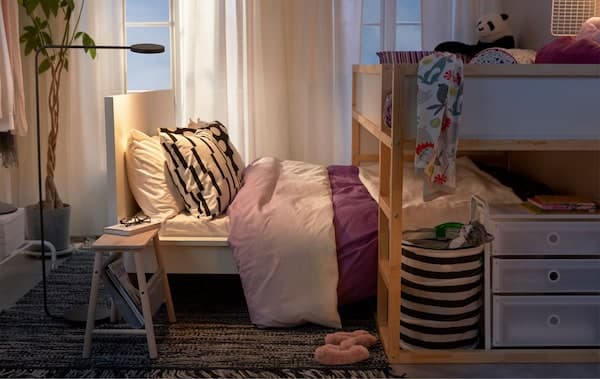 Loft bed standing across a lower bed, as a child’s bed straddling the parents’, in a small-space bedroom.