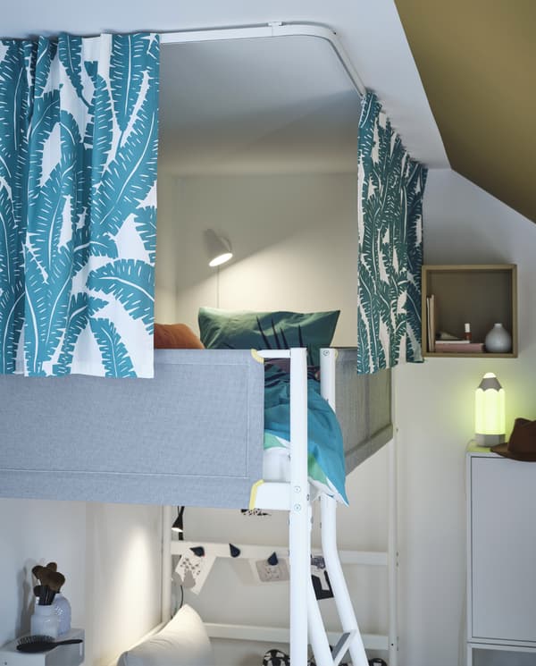 Loft bed surrounded by white/turquoise curtains that hang from ceiling-mounted track rails. The curtains provide privacy.