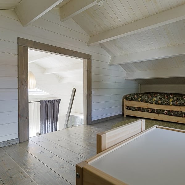 Loft bedroom area in wooden tiny house with sloped ceiling
