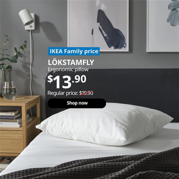 LOKSTAMFLY back sleeper pillow on top of a SLATTUM bedframe with a mattress, next to a bamboo wood side table. Words on image "IKEA Family price, LOKSTAMFLY, Ergonomic pillow, $13.90, Regular price: $19.90 with a slash, shop now". 
