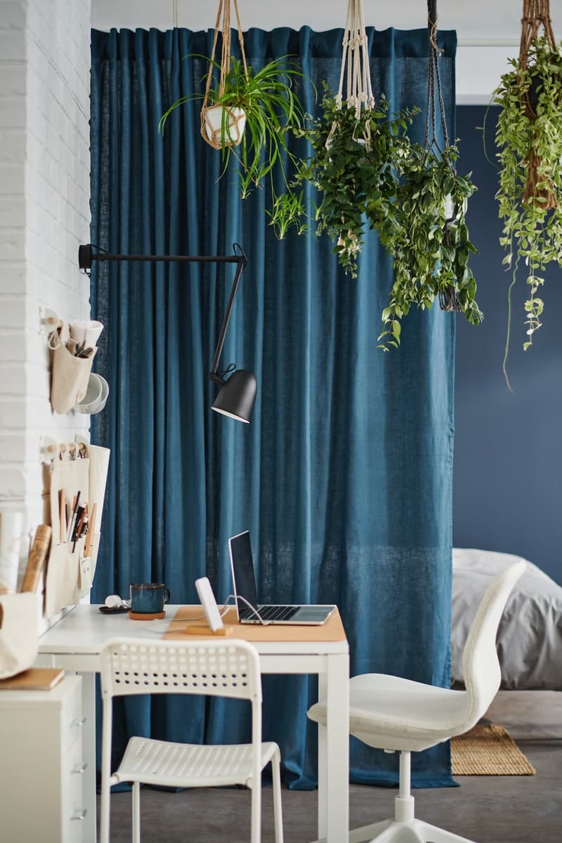 Long DYTÅG curtains hang down to the floor beside a window and then extend out into the room to divide up the space.