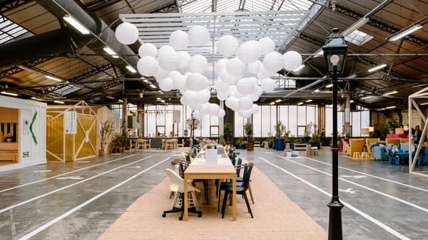 longue table au milieu d'un hall avec plusieurs chaises et des ballons blanc au-dessus de la table.
