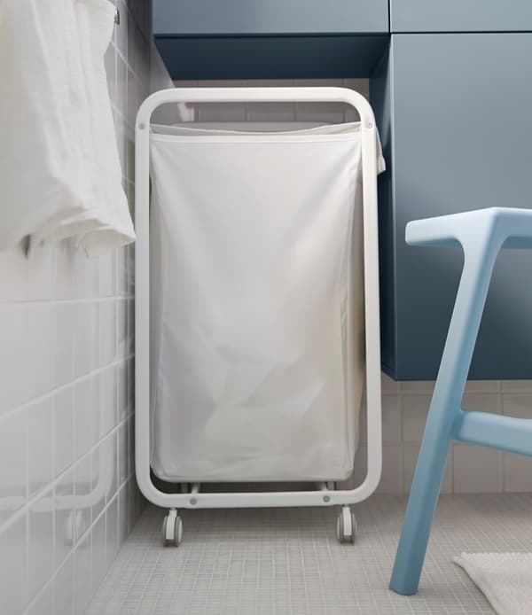Looking for big storage in a small bathroom? One tip is to design a space in between wall cabinets for other things  like this laundry basket.