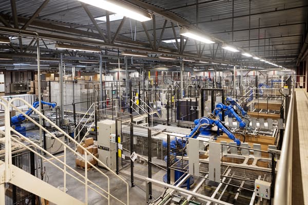Lots of robots line up in a production line in a factory building.