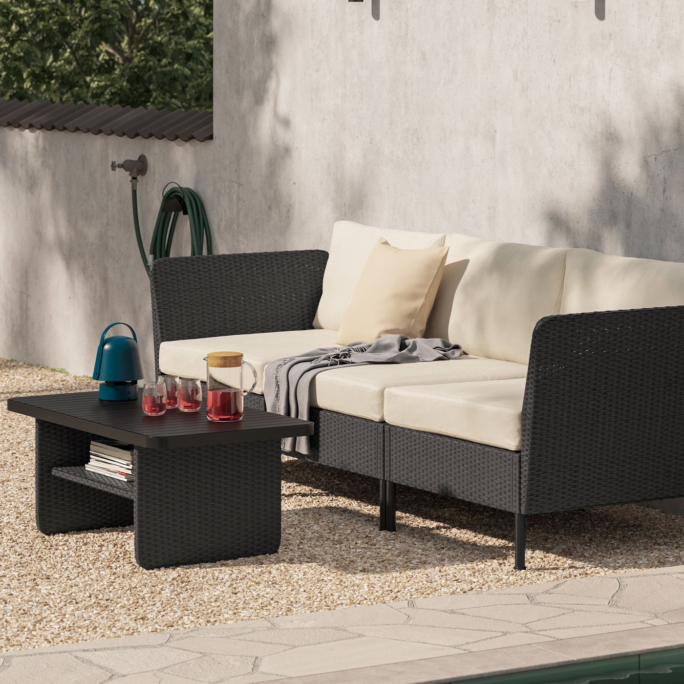 Loungesoffa i konstrotting med beige dynor och matchande bord. 