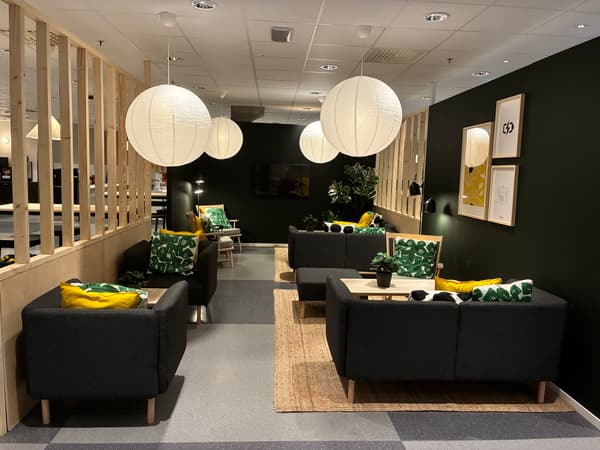 Loungeyta i IKEA Malmös personalmatsal med mörka soffor, träavskärmning, mjuk belysning och gröna textilier som skapar en lugn och avkopplande miljö.
