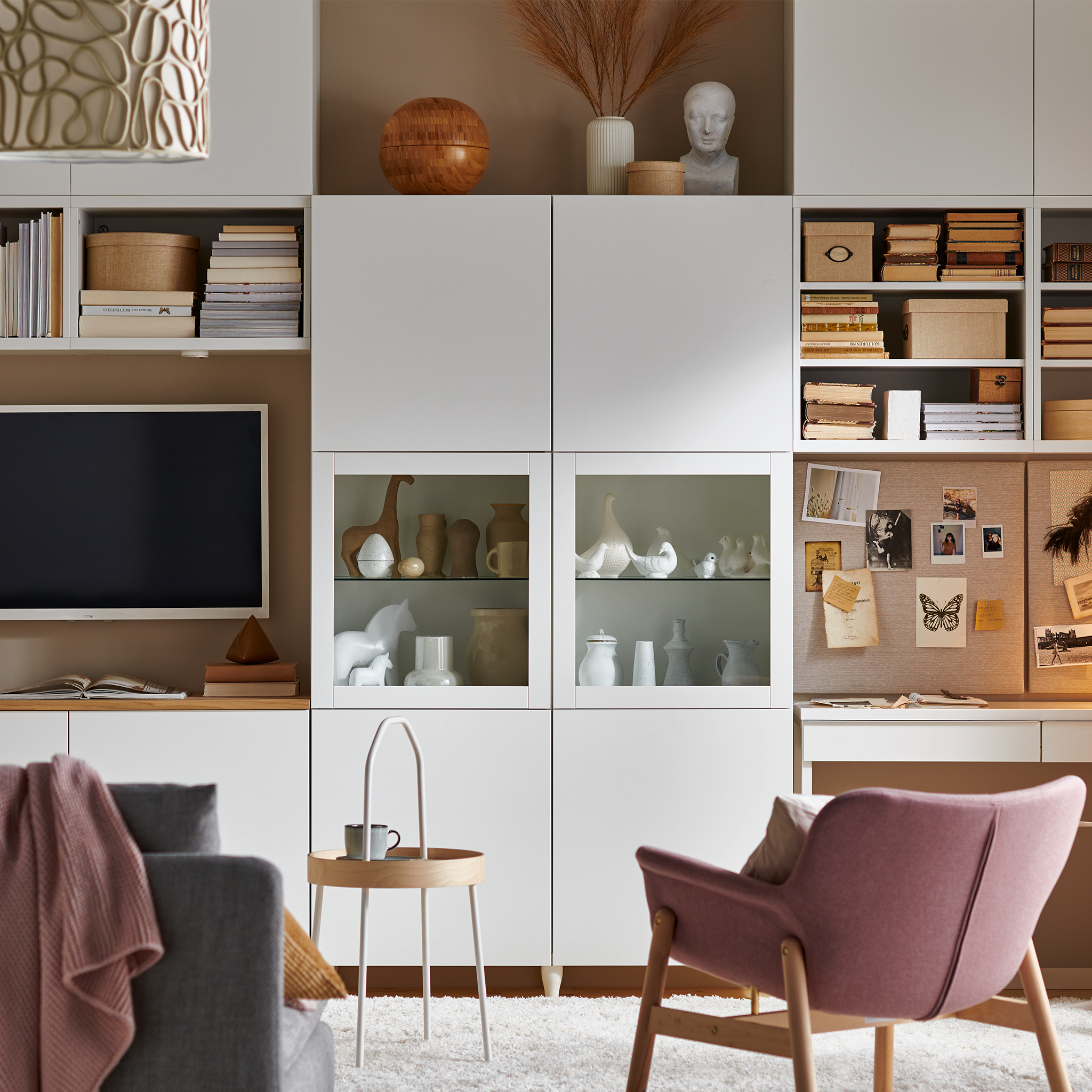 Low white BESTÅ storage unit with doors placed behind a sofa