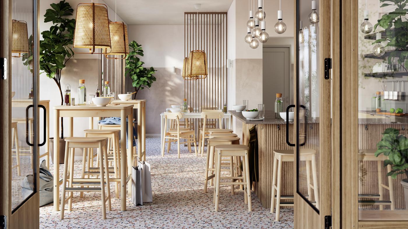 Lys og luftig restaurant med RÖNNINGE barbord og barkrakker av bjørk ryddig plassert under KNIXHULT taklamper av bambus.