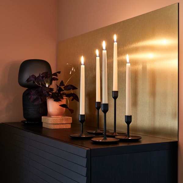 LYSEKIL لوح حائط بلون نحاسي، وشموع بيضاء، إناء نباتات أحمر-بني ومصباح طاولة أسود.