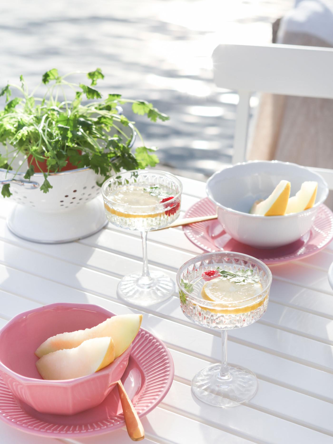 Lyserødt service og to SÄLLSKAPLIG champagneglas på et hvidt bord.