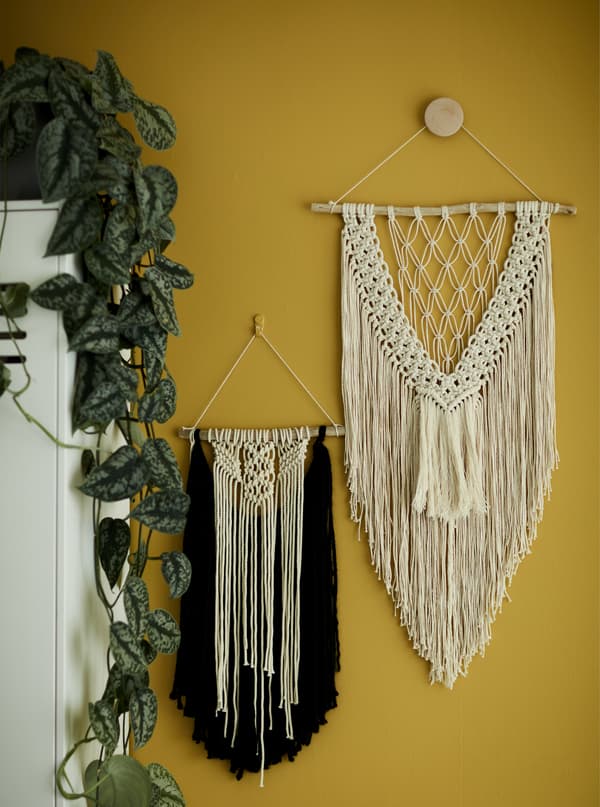 Macramé wall hangings on a yellow wall.