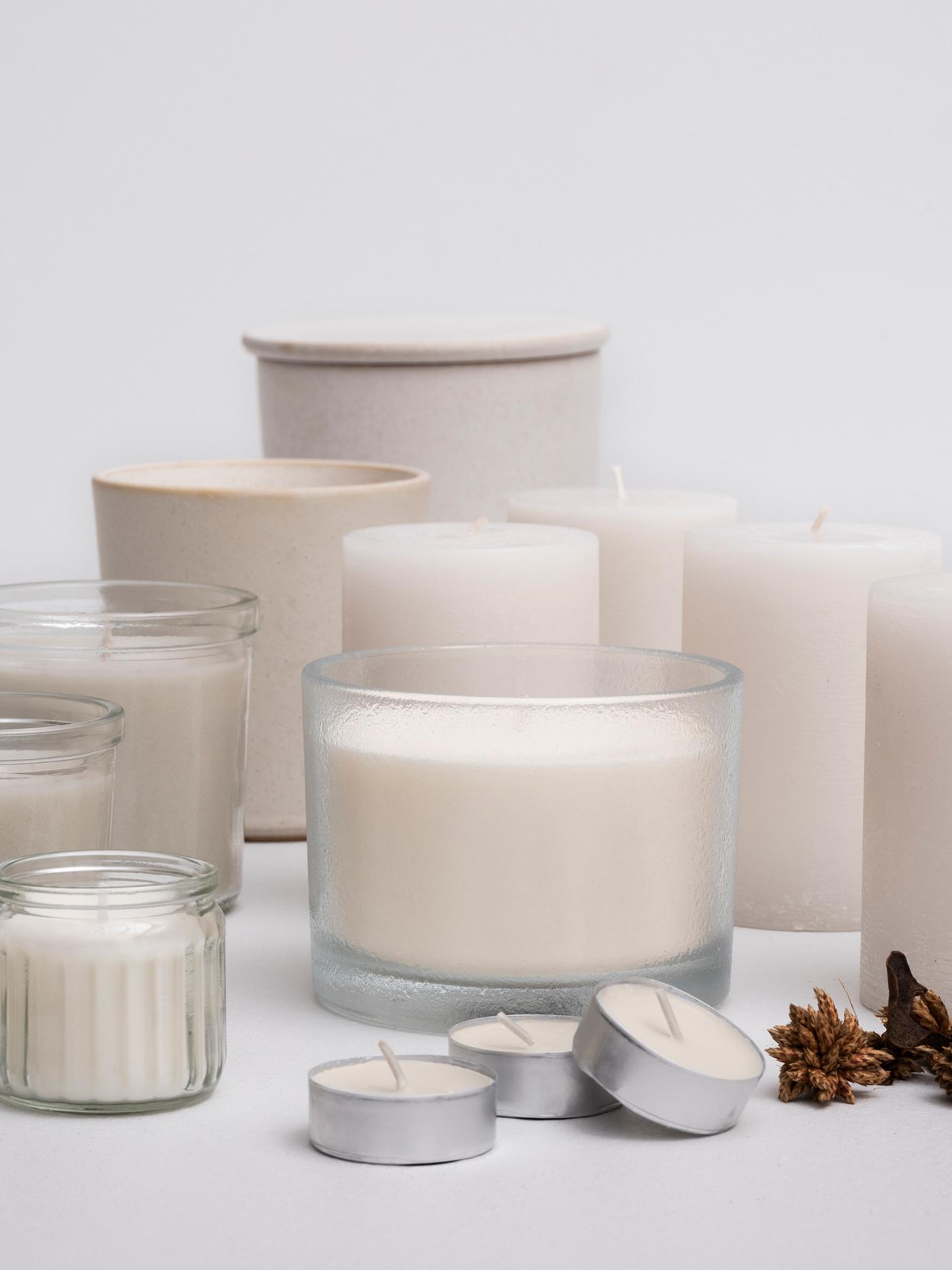 Mai multe lumânări parfumate ADLAD cu aromă de pădure scandinavă în diferite recipiente, pe un fundal gri deschis.