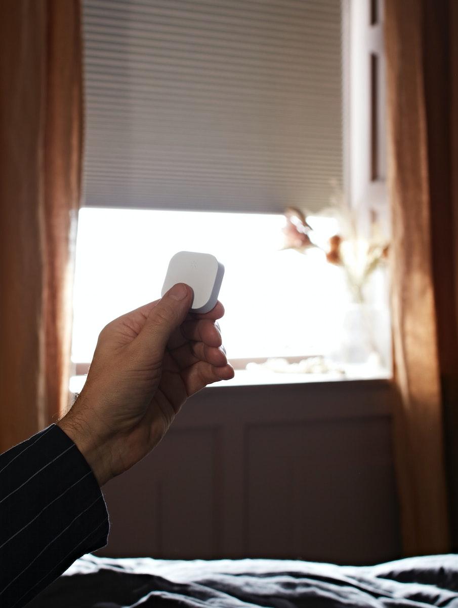 Main tenant une télécommande pour éclairage connecté IKEA. 