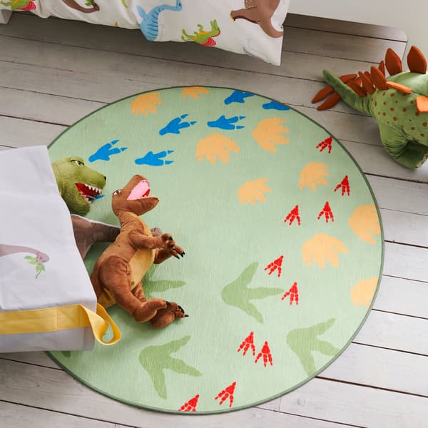 Mainan lembut dinosaur terlantar di atas ambal JÄTTELIK yang menampilkan corak kesan jejak kaki dinosaur diletakkan di dalam bilik tidur kanak-kanak.