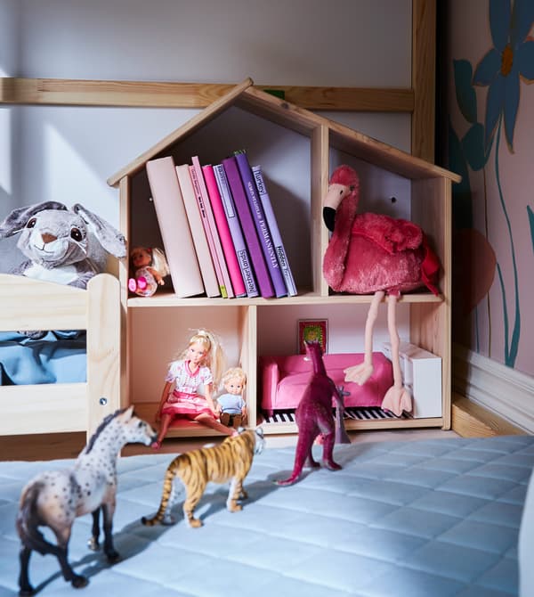 Maison de poupées remplie de jouets et de livres et lit de poupée, dans un coin jeu pour enfant.