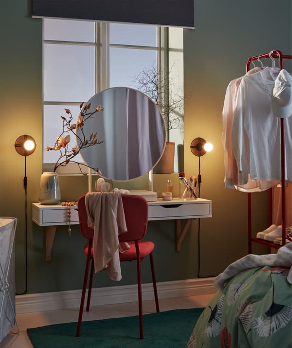 Make-up spot, under a window, with a round mirror, wall shelf with drawers as a small worktop, chair and lighting.